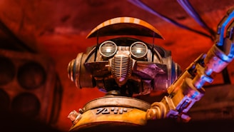 A robot with large circular eyes, a mechanical mouthpiece, and an articulated arm set against a warm, reddish background. The metal features have a worn, rustic appearance, adding a sense of vintage charm.