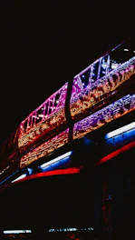A sleek, futuristic train gliding through a vibrant cityscape under a colorful aurora-lit sky.