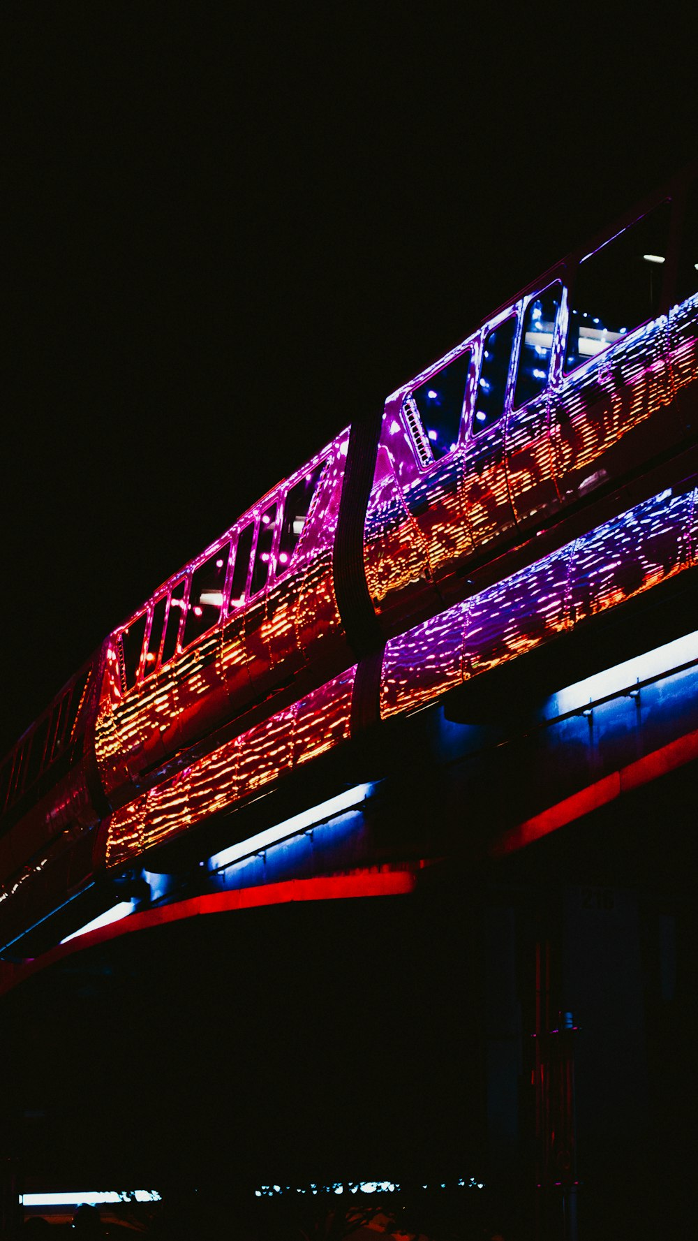 a lit up train traveling over a bridge at night