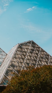 A stunning stainless steel pyramid structure in a lush green landscape.