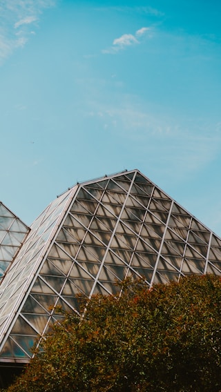 A stunning stainless steel pyramid structure in a lush green landscape.