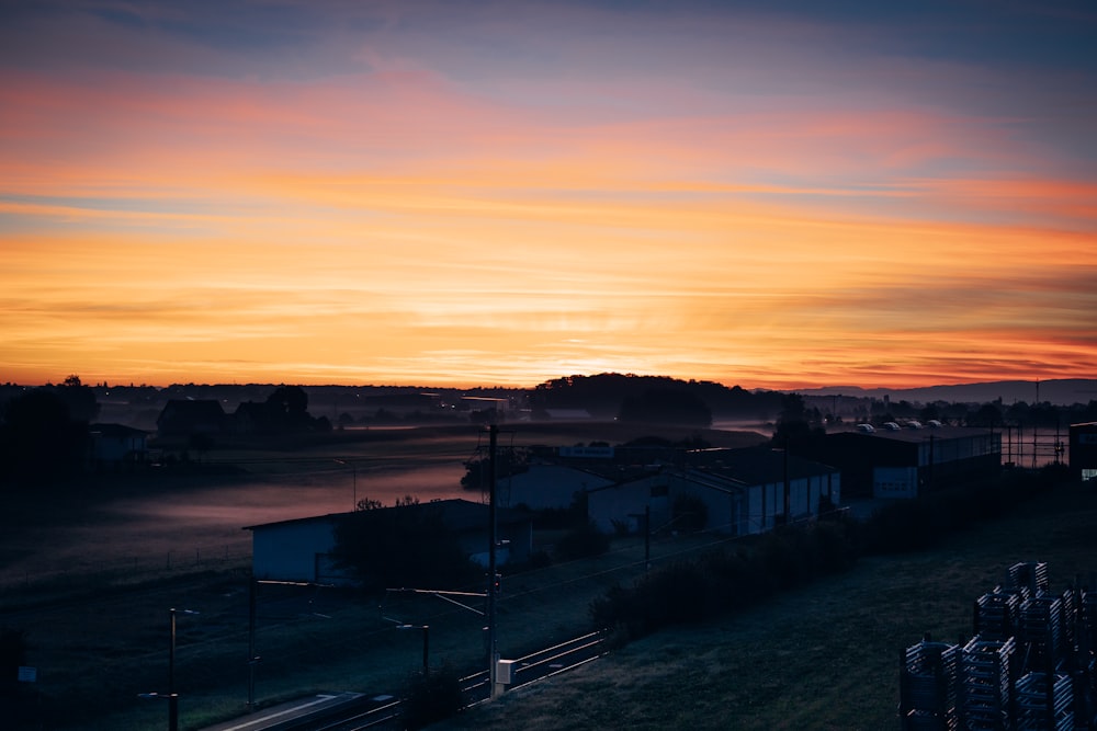 a sunset over a field with a train on the tracks