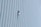 A person wearing safety gear is suspended by ropes, performing maintenance or cleaning on the side of a large building with vertical panels.
