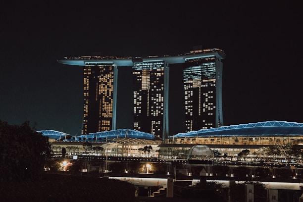 A sleek nighttime aerial view of The Enclave showcasing its illuminated 124ft commercial boulevard and modern fortress design.
