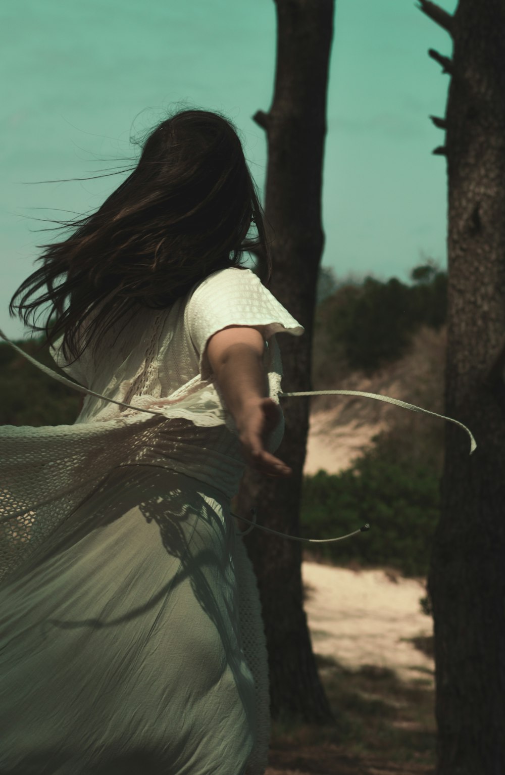 a woman in a white dress is flying a kite