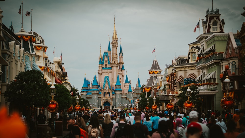 a crowd of people walking down a street in front of a castle