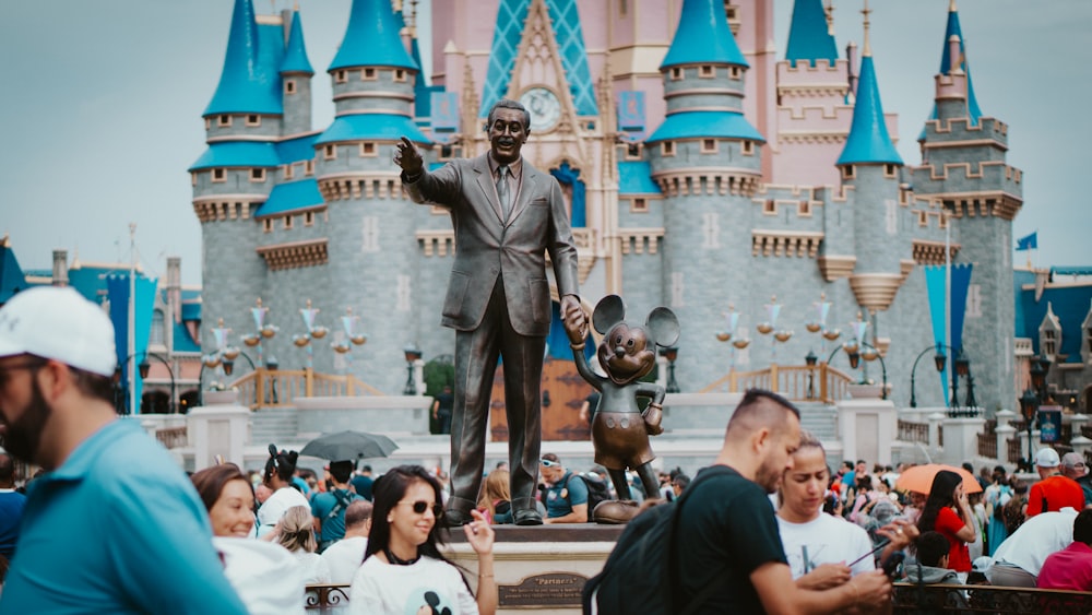 a crowd of people standing around a statue of mickey mouse