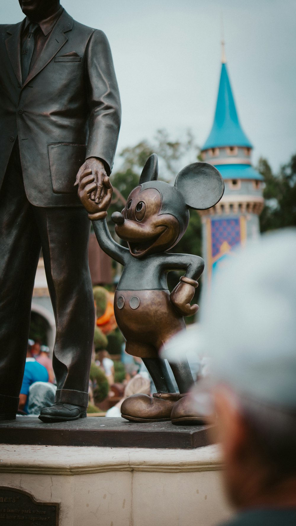 a statue of a man holding the hand of a mickey mouse