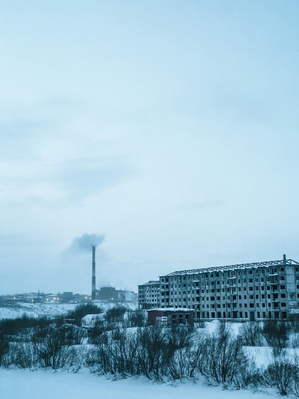 a factory in the distance with snow on the ground