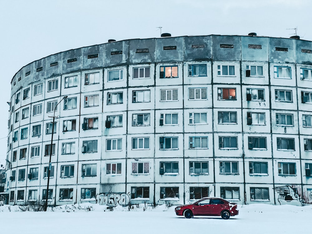 a red car parked in front of a large building