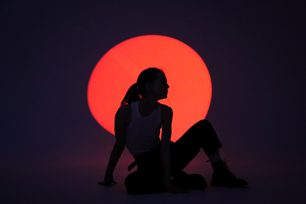 a woman sitting in front of a red sun