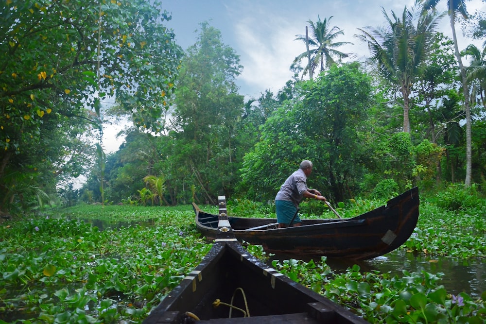 a man standing on a boat in a swampy area