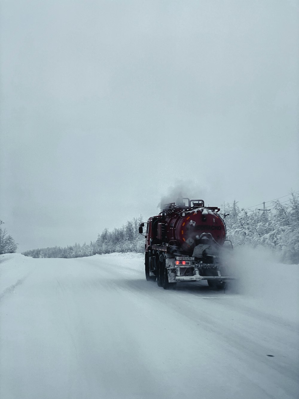 a large truck driving down a snow covered road