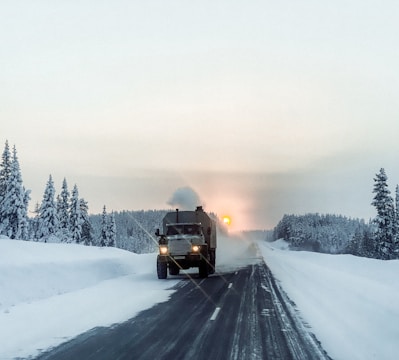 a large truck driving down a snow covered road