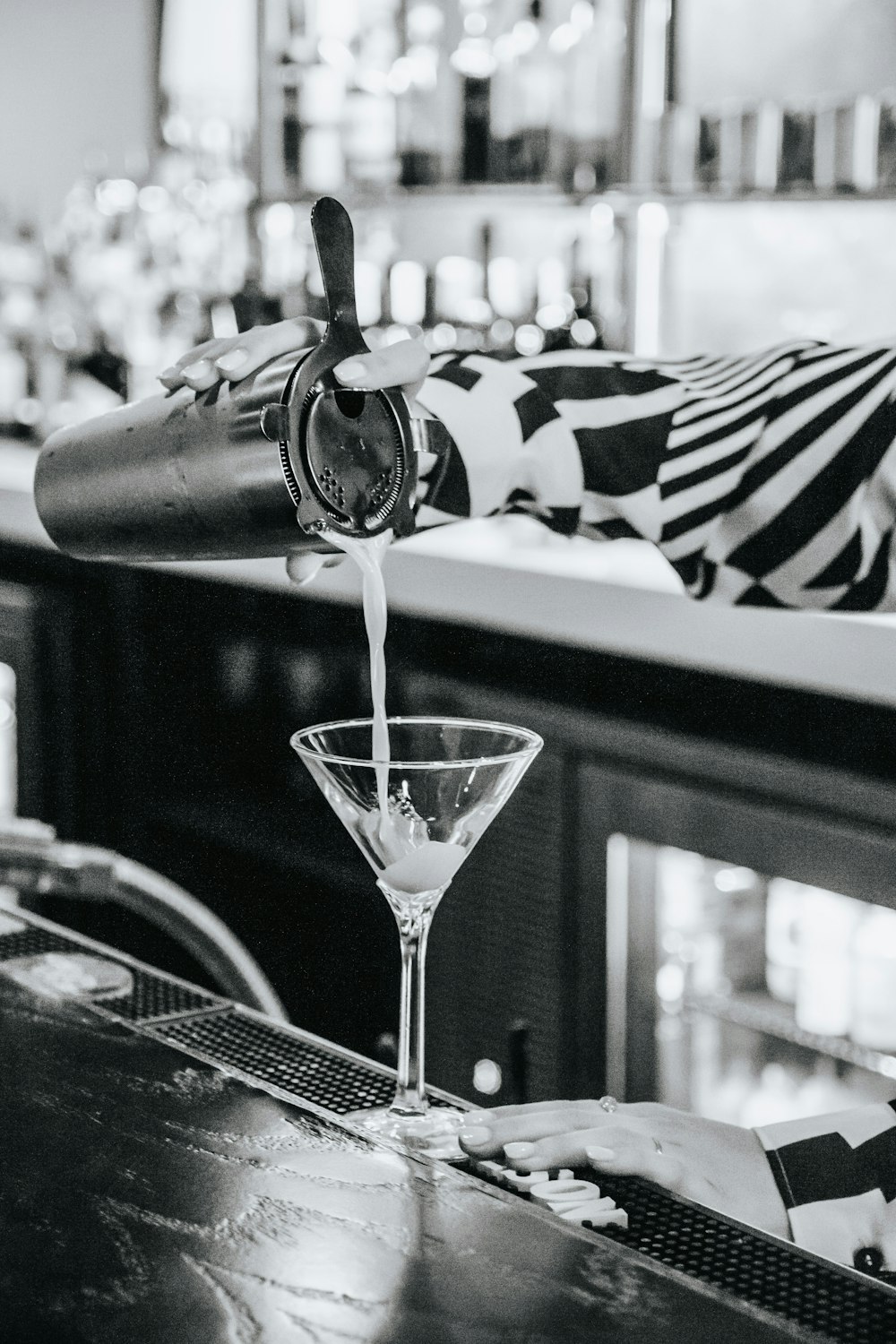 a person pouring a martini into a martini glass