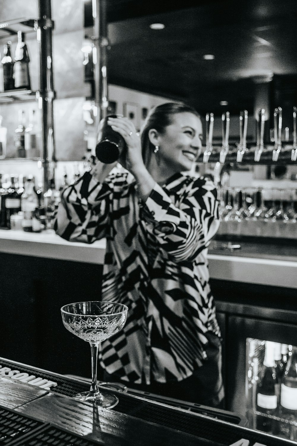a woman standing at a bar pouring a drink