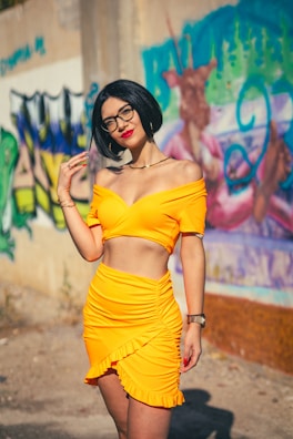Aura Sterling in a bold, colorful outfit standing confidently against a graffiti wall.