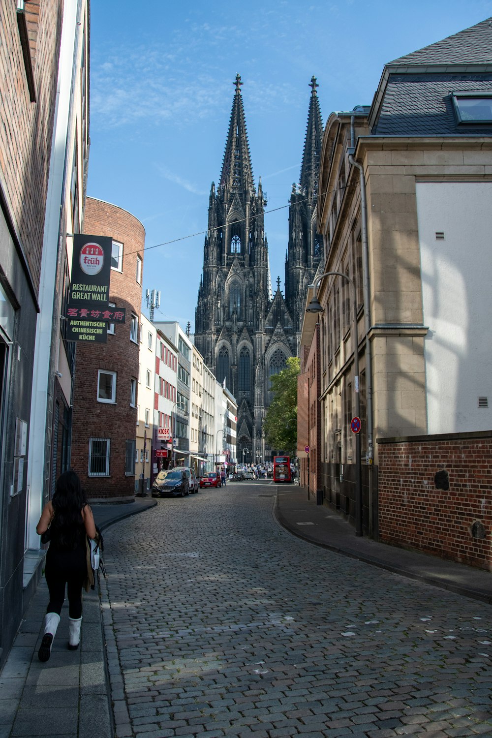 a woman is walking down a cobblestone street