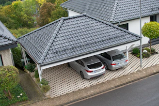 Cars parked safely under a covered area with a home in the background.