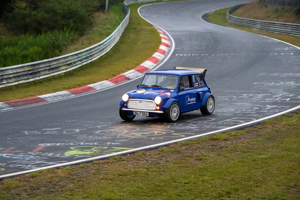 um pequeno carro azul dirigindo por uma pista de corrida