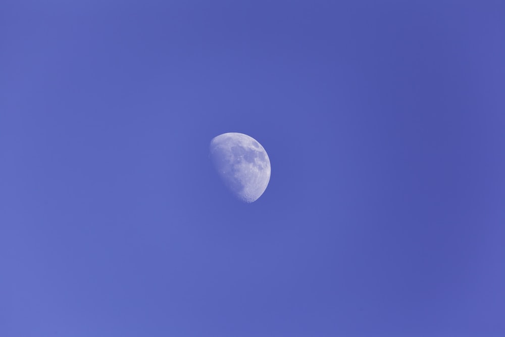 a half moon is seen in a blue sky