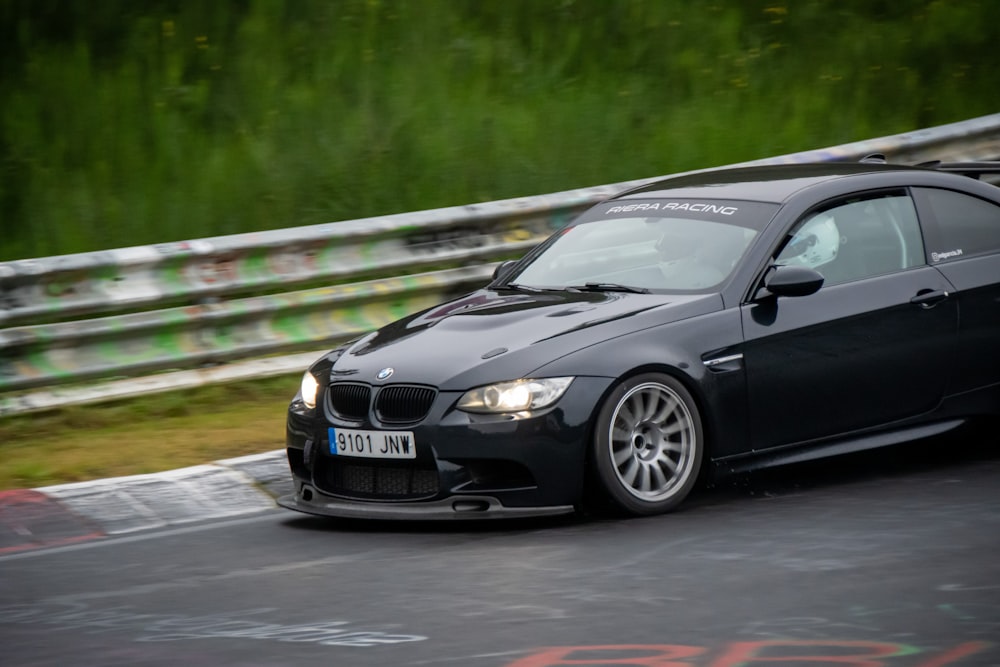 a black car driving down a race track