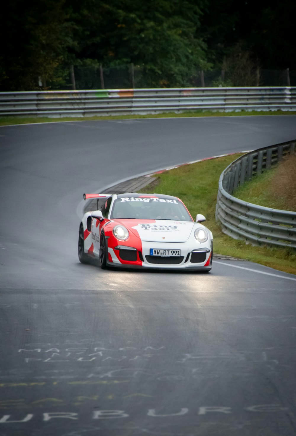 a red and white car driving down a race track