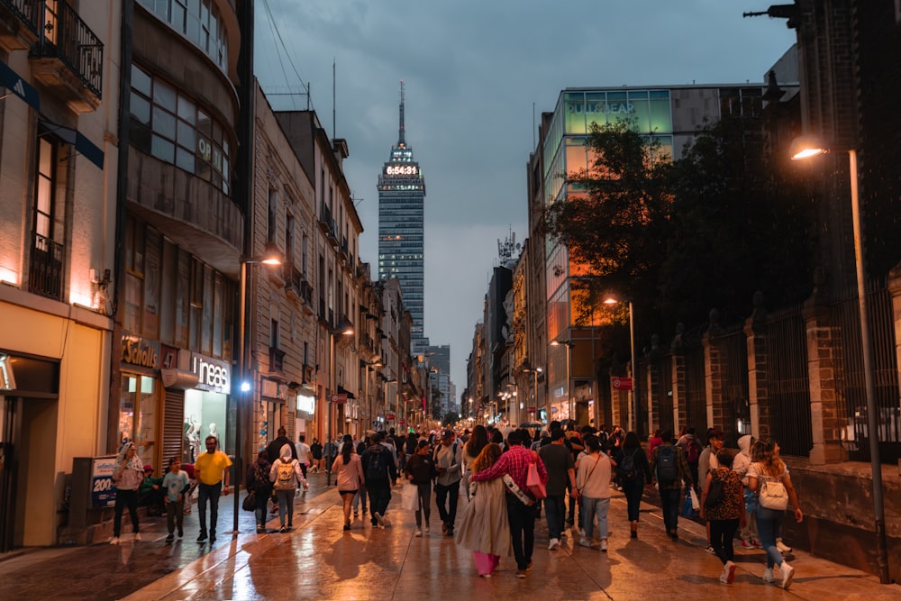 a group of people walking down a street next to tall buildings