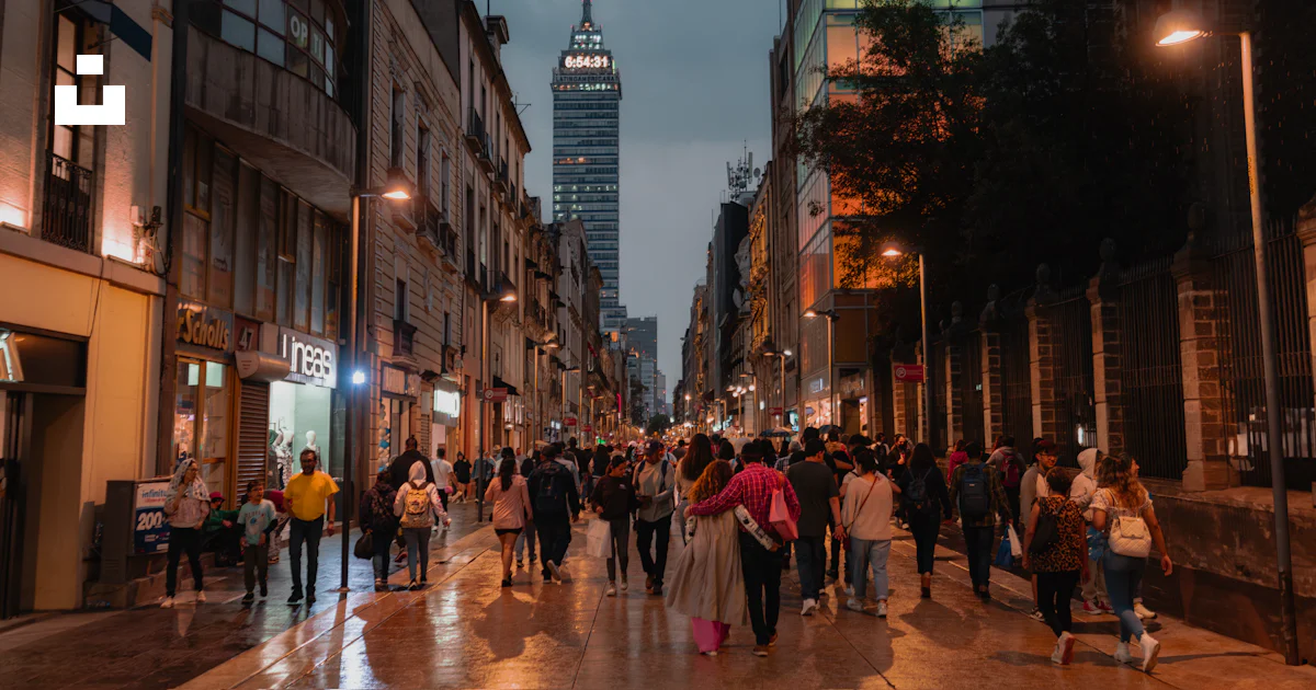 Un Grupo De Personas Caminando Por Una Calle Junto A Edificios Altos un-grupo-de-personas-caminando-por-una-calle-junto-a-edificios-altos