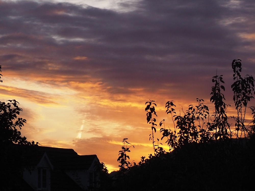 the sun is setting over a house and trees