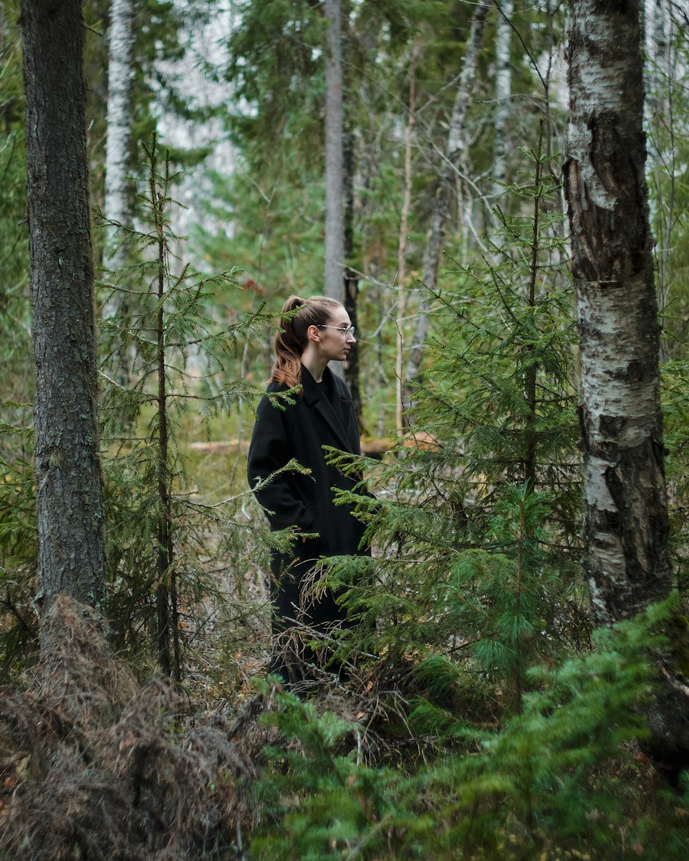 a woman standing in a forest with trees