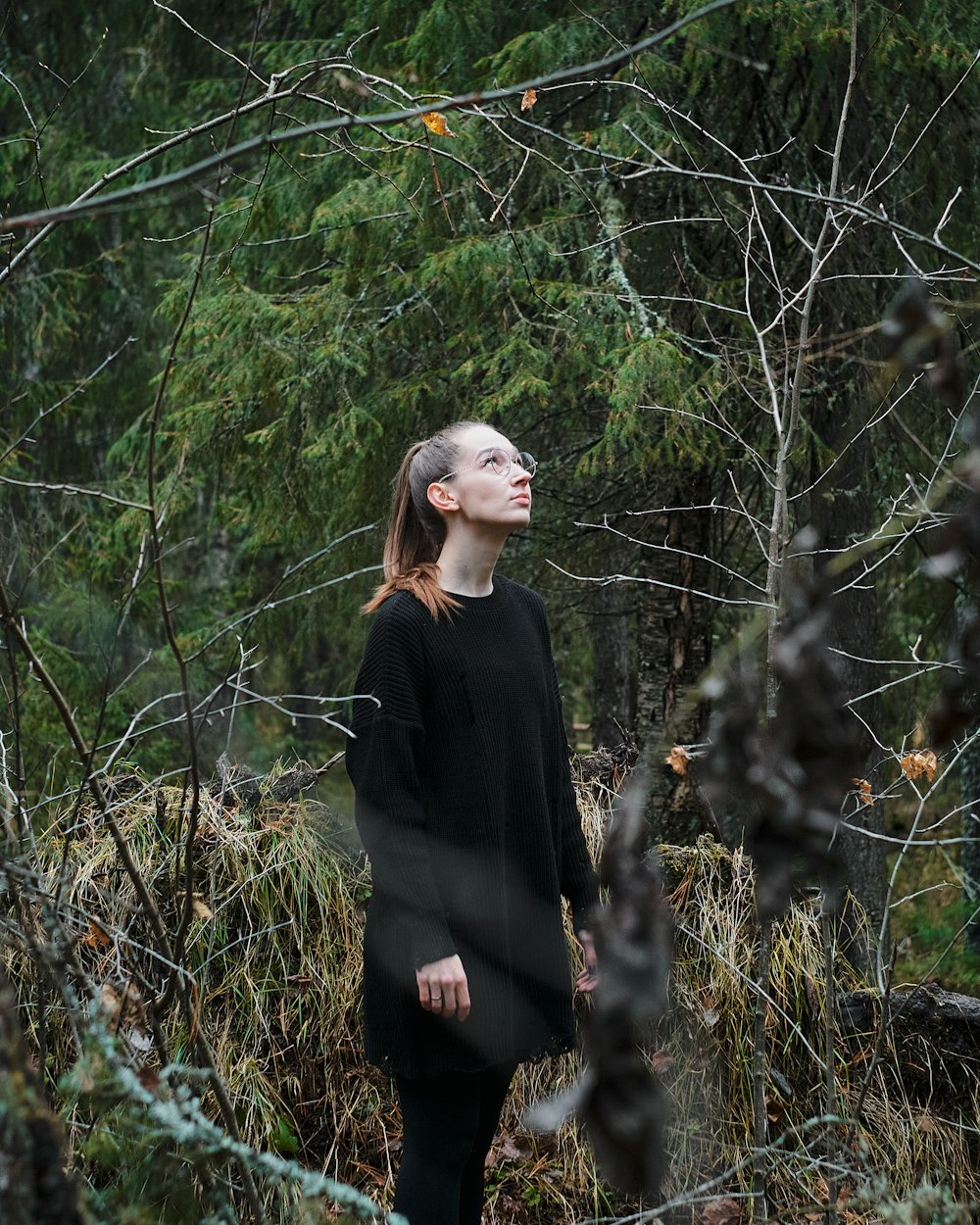 a woman standing in the middle of a forest