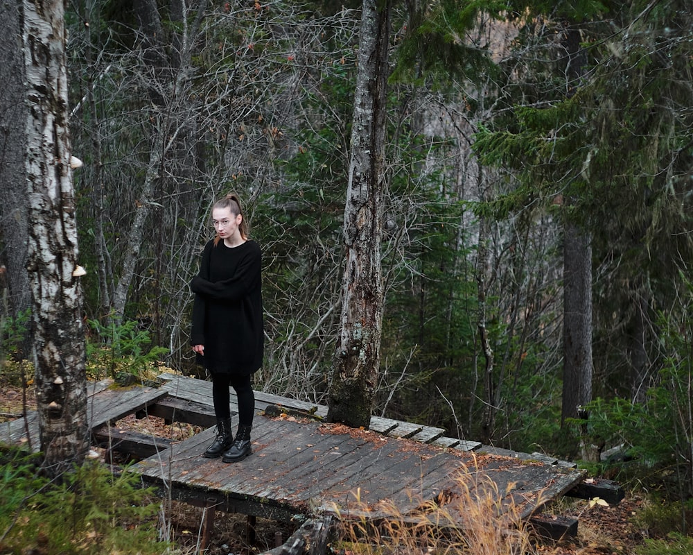 a woman standing on a wooden platform in the woods