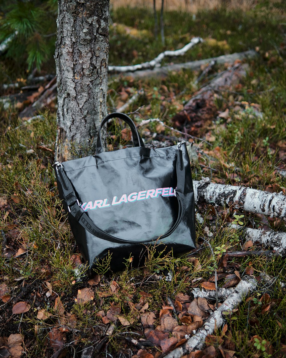 a black bag sitting in the grass next to a tree