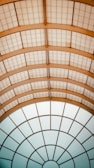 A ceiling structure with a series of geometric patterns, featuring a combination of rectangular and circular grid designs. The ceiling is composed of translucent panels with a metal framework, creating a modern and architectural aesthetic.