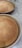 Two freshly baked, golden brown loaves of bread sit in round baking pans on a speckled countertop. The bread is evenly baked, creating a smooth and slightly domed surface.