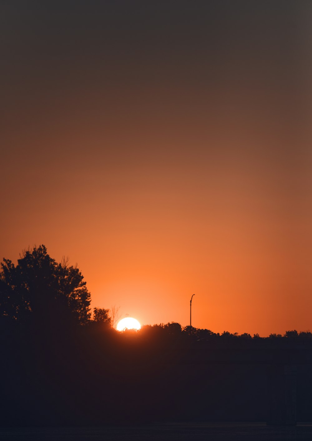 the sun is setting behind a tree line