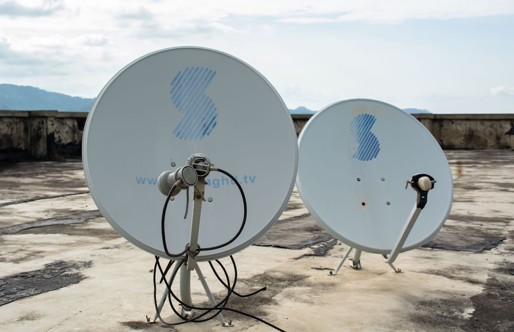 a couple of satellite dishes sitting on top of a cement ground