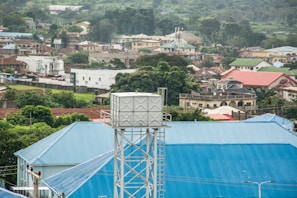 A horizontal water tank placed on a rooftop with lush green Kerala hills in the background under a clear blue sky.