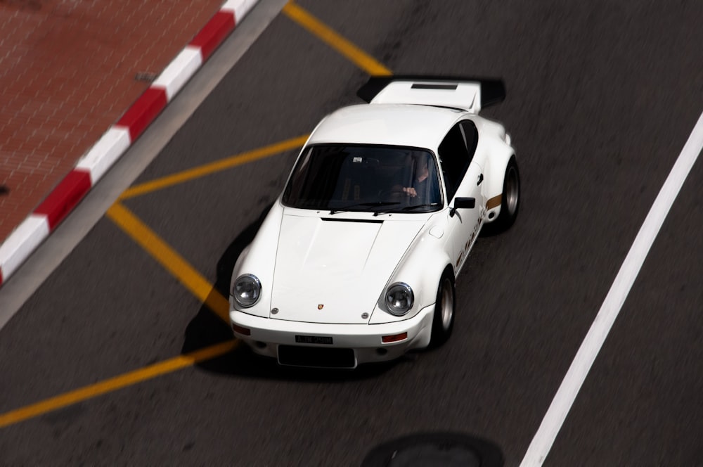 a white sports car driving down a street