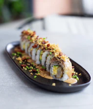 A vibrant sushi roll being wrapped to go in a modern, casual setting.