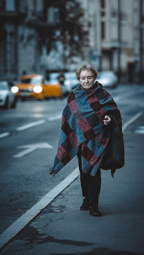 a woman is walking down the street with a blanket
