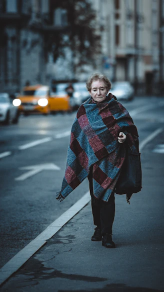 a woman is walking down the street with a blanket