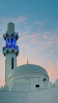 A peaceful view of Masjid Bukit Palma at sunset with soft warm lighting highlighting its architecture.