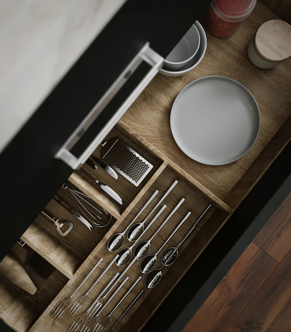 An organized kitchen drawer with neatly arranged utensils and compact storage containers, showcasing practical use of space.