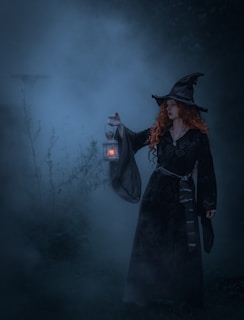 a woman dressed as a witch holding a lantern