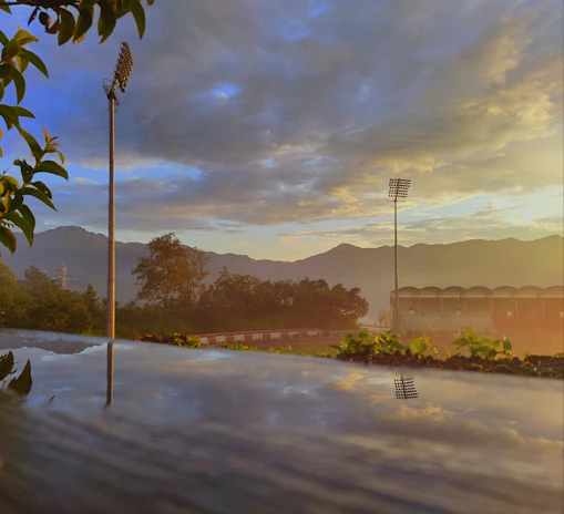 A panoramic view of a packed stadium with a dramatic sunset backdrop and buzzing atmosphere.