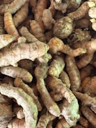 Close-up of fresh turmeric roots stacked neatly in a wooden crate.
