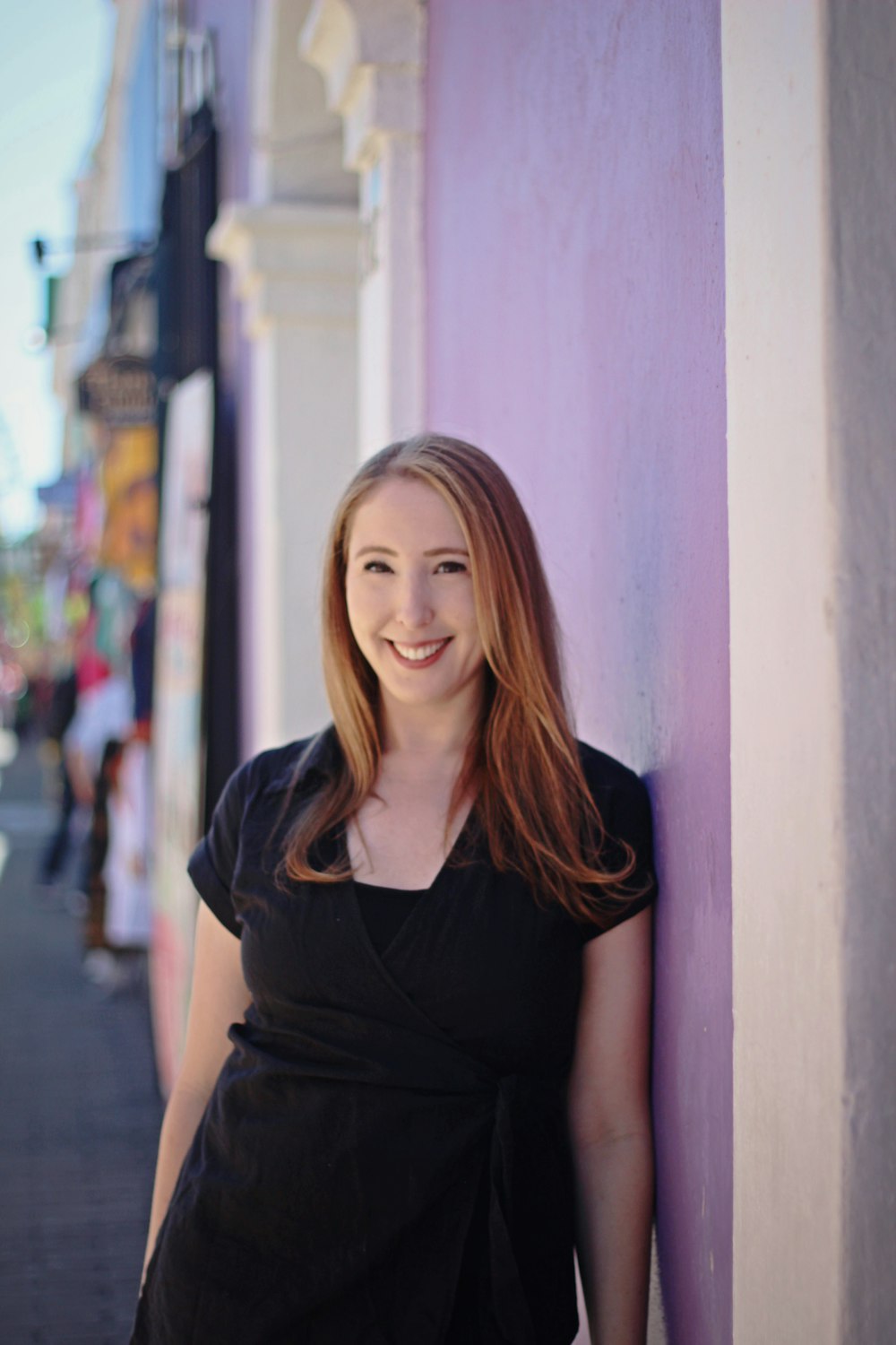 a woman standing next to a purple wall