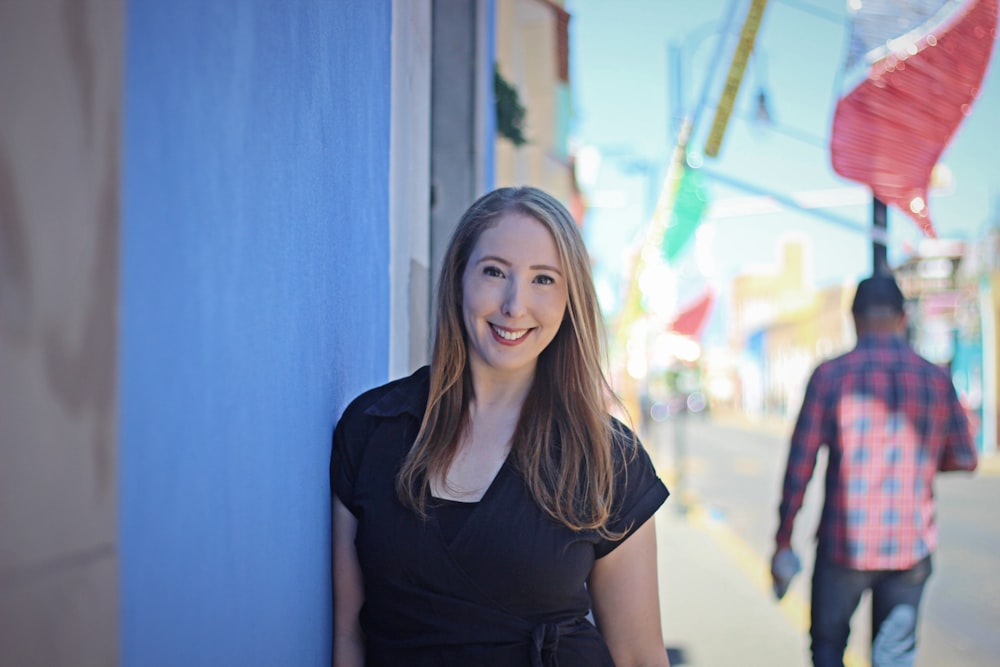 a woman standing next to a blue wall